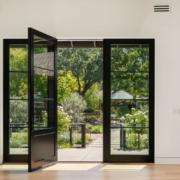 Open black framed glass doors leading from a living room to a garden patio Los Angeles