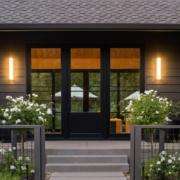 replacement-doors-Orange-County-CA Modern house entrance with black double doors, wall lights, and flower planters in Orange County