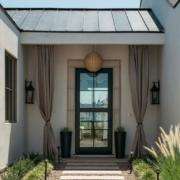 Covered entryway with a glass front door, stone walls, and decorative plants in Yorba Linda
