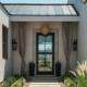 Covered entryway with a glass front door, stone walls, and decorative plants in Yorba Linda