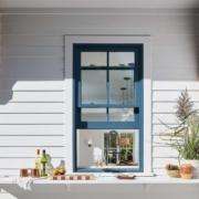 Replacement windows Yorba Linda, CA with a blue-framed window on a modern white home exterior
