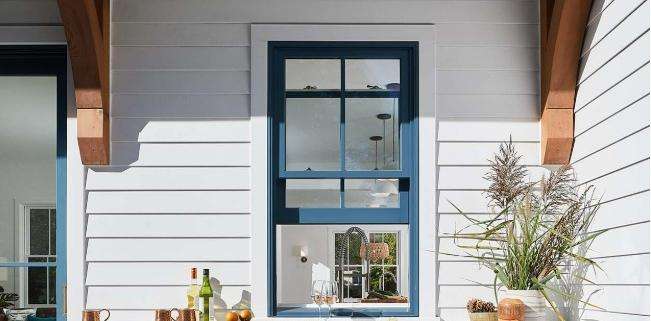 Replacement windows Yorba Linda, CA with a blue-framed window on a modern white home exterior